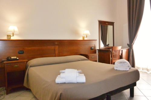 Hotel Trentina في ميلانو: غرفة فندق عليها سرير وفوط