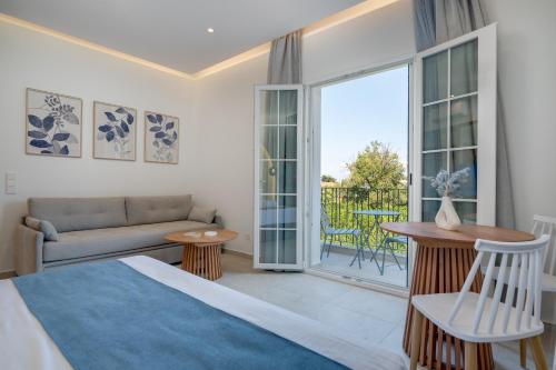 a bedroom with a bed and a couch and a balcony at Secret Garden Studios in Mytilene