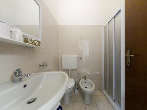 a white bathroom with a toilet and a sink at Hotel Trentina in Milan