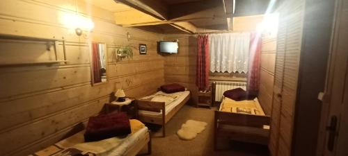 a room with three beds and a tv in it at U Sarapatki-Noclegi z wyżywieniem in Jurgów