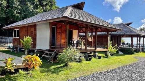 a small wooden cabin with a porch on a lawn at Lodge ORION - Coté Piscine in Uturoa