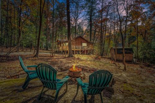 two chairs and a table with a fire in front of a cabin at Cabin at Sleepy Creek - Creek Access, Wifi, Pet Friendly, Fire Pit, Charcoal Grill, Screen Porch, Wood Stove, Deck, Family Friendly in Berkeley Springs