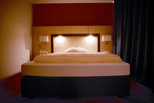 a large bed in a bedroom with a red wall at Ringhotel Appelbaum Gütersloh in Gütersloh