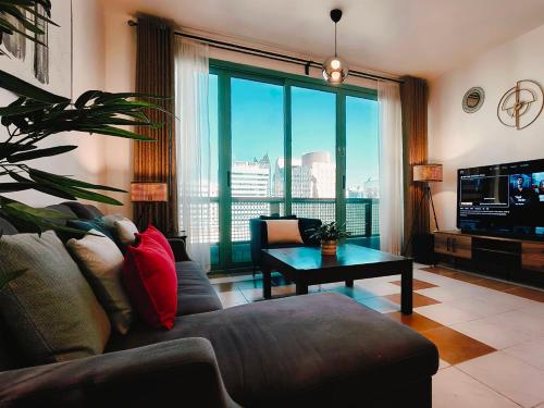 a living room with a couch and a large window at One Guest Place Deluxe Room near the Beach in Abu Dhabi