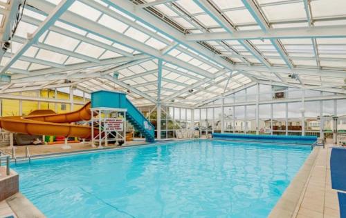 a large swimming pool with a water slide in a building at Summer Breeze Deluxe Coastfields , ingoldmells in Skegness