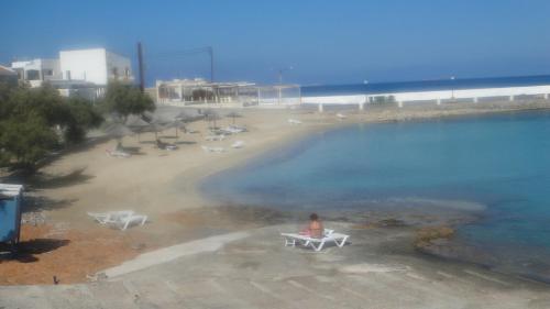a woman sitting on a chair next to a beach at AVRA Apartments & Studios in Frý