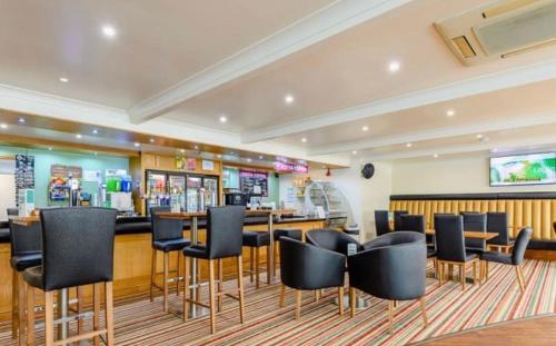 a bar with black chairs in a restaurant at Summer Breeze Deluxe Coastfields , ingoldmells in Skegness