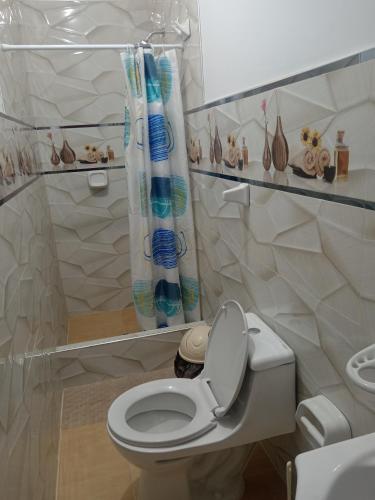 a bathroom with a white toilet and a shower curtain at La Casa Del Hombre in Puerto Chicama