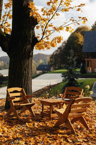 three wooden benches sitting next to a tree at Apartamenty Greenwood in Staniszów