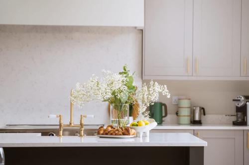 a kitchen counter with a vase of flowers and a bowl of fruit at Our House Collective - Luxury Stay in Lincoln City Centre, Hot tub, Sleeps 16 in Lincoln