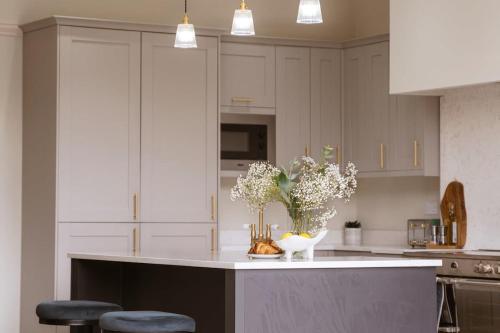 a kitchen with white cabinets and a counter with flowers on it at Our House Collective - Luxury Stay in Lincoln City Centre, Hot tub, Sleeps 16 in Lincoln