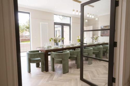 a dining room with a table and green chairs at Our House Collective - Luxury Stay in Lincoln City Centre, Hot tub, Sleeps 16 in Lincoln
