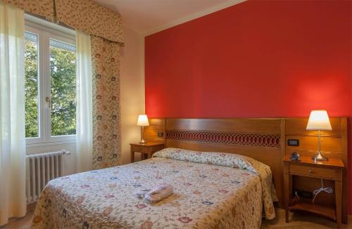 1 dormitorio con cama y pared roja en Park Hotel Fantoni, en Tabiano