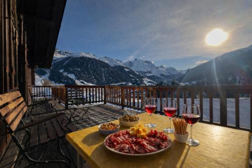 a table with a plate of food and two glasses of wine at Chalet Le Zirizui - Authentique refuge alpin avec vue imprenable in Liddes