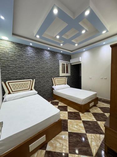 two beds in a room with a checkered floor at Apartment 18 Maspero in Alexandria