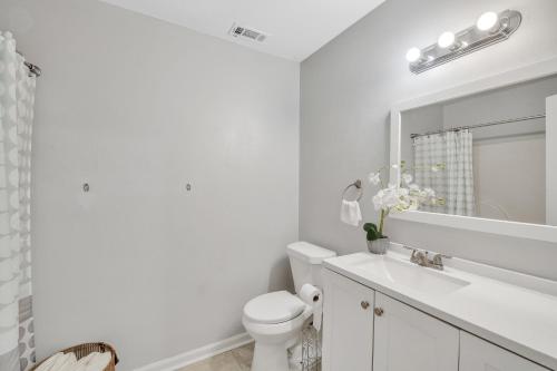 a white bathroom with a toilet and a sink at Uptown Serenity in North Little Rock