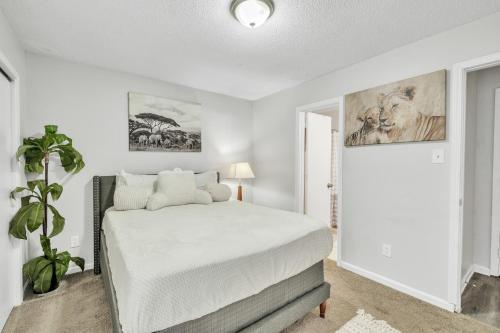 a white bedroom with a bed and a plant at Uptown Serenity in North Little Rock