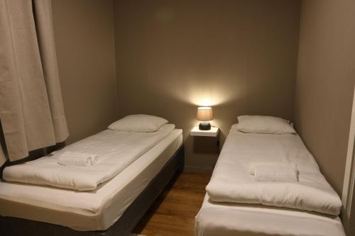 two beds in a small room with a lamp at Cozy House in Tromsø - Near City Center, Ideal for Families & Groups in Tromsø