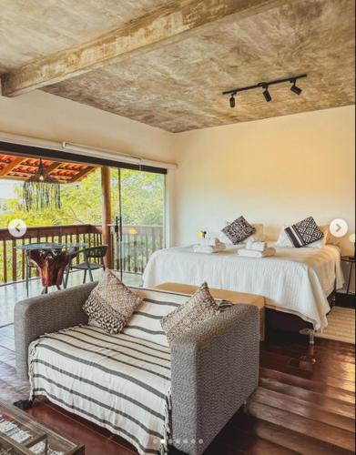 a bedroom with a bed and a couch and a balcony at Pousada Caminho Das Cachoeiras in Sao Jorge