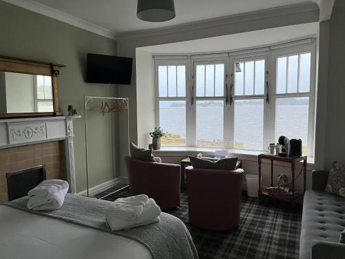 a room with a bed and chairs and a fireplace at The Rhu Inn in Rhu