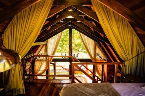 a room with a bed and a window with curtains at Chalet Relaggio in Encantado