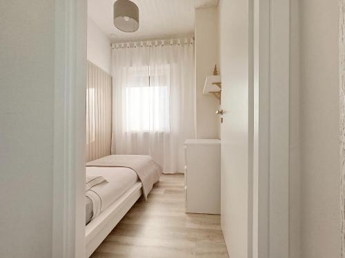 a white bedroom with a bed and a window at Kasakiwi Apartment in Vicenza