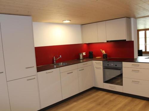 a kitchen with white cabinets and a red wall at Apartment Leinacherhof by Interhome in Seeberg