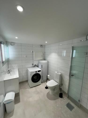 a bathroom with a washing machine and a toilet at Skolegata 6B, 9404 Harstad in Harstad