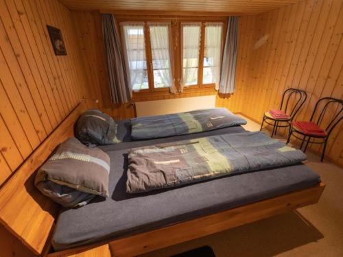 two beds in a wooden room with two chairs at Apartment Muessache by Interhome in Dürrenroth