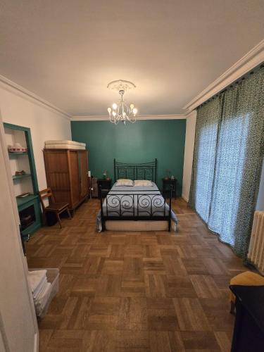 a bedroom with a bed and a chandelier at La maison bleue avec une grande piscine chauffée in Bozouls
