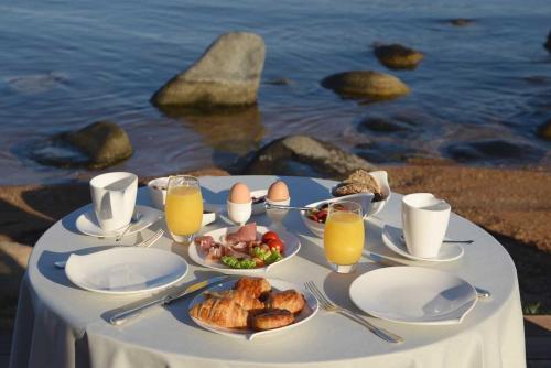 a table with plates of food and glasses of orange juice at Hôtel Le Belvédère in Porto-Vecchio