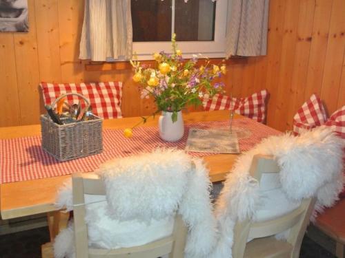 a dining room table with a vase of flowers on it at Apartment Huusli by Interhome in Axalp