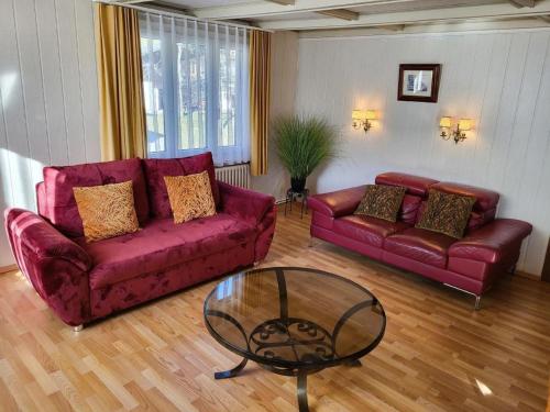 a living room with two red couches and a glass table at Apartment Chalet Lilo Big view by Interhome in Beatenberg