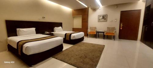 a hotel room with two beds and a table and chairs at The Avenue Hotel & Suites in Chittagong