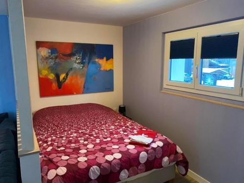 a bedroom with a bed with a red comforter and two windows at Apartment Spring Inn Studio by Interhome in Rohrmatten
