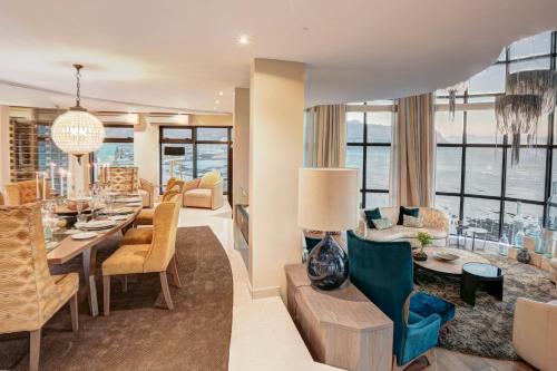 a dining room and living room with a view of the ocean at Ocean View Penthouse in Strand