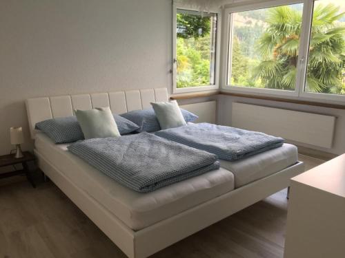 a bed with pillows on it in a room with two windows at Apartment Weggis by Interhome in Weggis