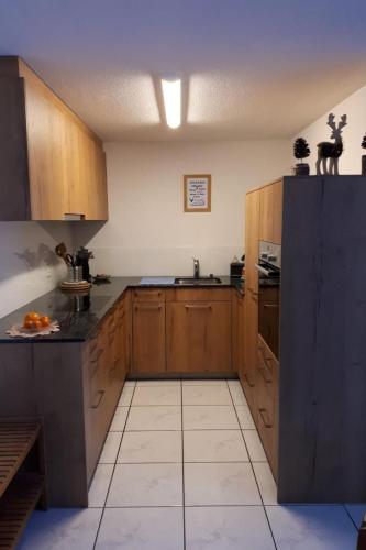 a large kitchen with wooden cabinets and a tile floor at Apartment Baldo by Interhome in Sörenberg