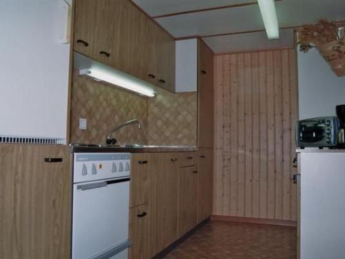 a kitchen with white appliances and wooden cabinets at Apartment Fruehalp by Interhome in Unterägeri