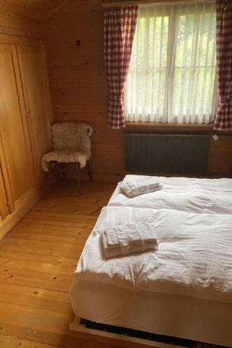 a bedroom with a bed and a chair and a window at Apartment Chalet Bacchus - OG by Interhome in Sörenberg