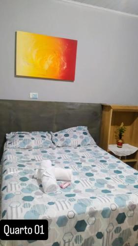 a bed with a blue and white comforter on it at Hostel Hotel uma otima opçao para suas ferias e um bom descanso in Cianorte