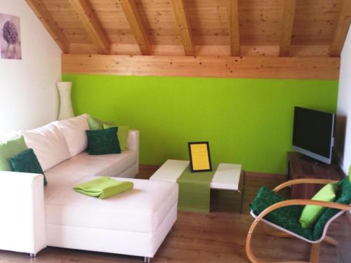 a living room with a white couch and a green wall at Apartment S'Ottä by Interhome in Sattel