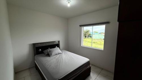 a small bedroom with a bed and a window at Duplex completo, perto da praia e no centro de Imbé in Imbé