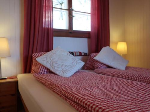 a bedroom with a bed with two pillows and a window at Apartment be und mee by Interhome in Rigi Kaltbad