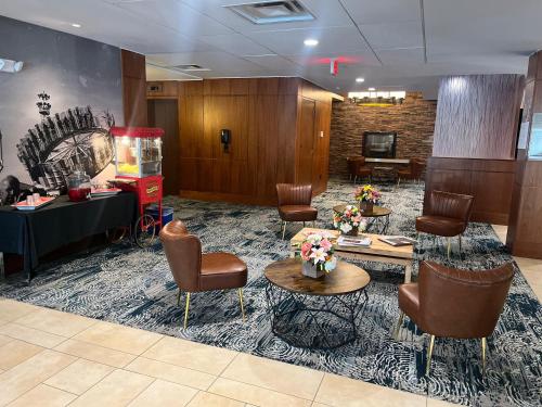a waiting room with chairs and tables and a television at Randolph Hotel Liverpool Syracuse Airport West, Trademark in Liverpool