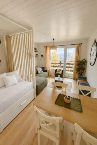 a bedroom with a bed and a living room with a table at Vue imprenable sur les Alpes et Parking privé gratuit in Crans-Montana