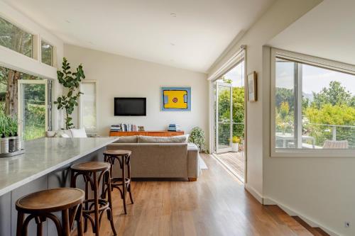 a kitchen and living room with a counter and stools at The Tailor's Terrace, Kangaroo Valley in Kangaroo Valley