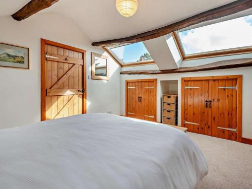 a bedroom with a large white bed and wooden cabinets at 3 Bed in Keswick oc-94346 in Threlkeld