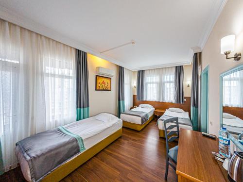ein Zimmer mit zwei Betten, einem Tisch und Stühlen in der Unterkunft Triana Hotel in Antalya