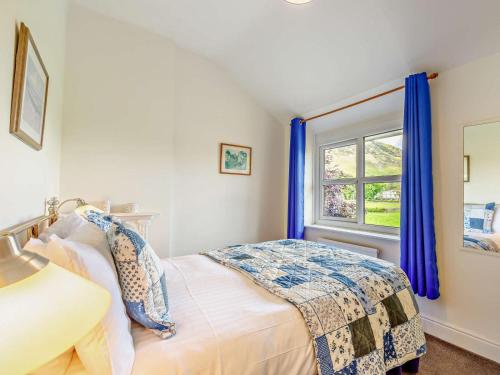a bedroom with a bed with blue curtains and a window at 3 Bed in Keswick oc-sz148 in Grange